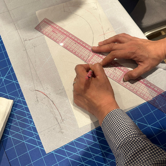 A close-up of hands using a KEARING brand, No 8002, Clear Plastic Straight Ruler, 50cm x 5cm, measuring with a pencil on a white drafting layout over a blue colour, Kai cutting mat, CB-143.