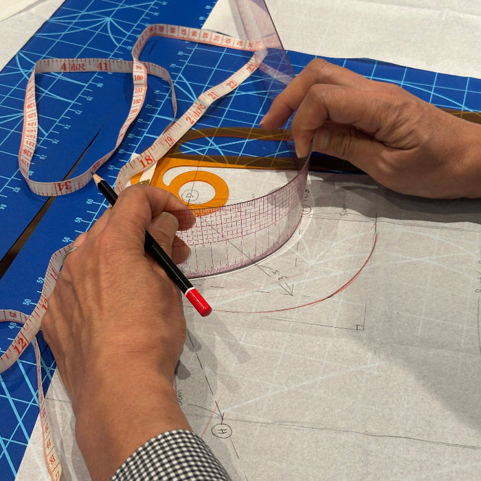 A close-up of hands using a clear curved measuring ruler with a pencil and tape measure on a white fabric layout over a blue cutting mat.
KEARING brand, No 8002, Clear Plastic Straight Ruler, 50cm x 5cm